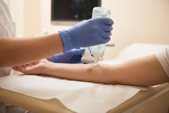 Sonographer applying ultrasound gel to scan a soft tissue lump on a patient's arm
